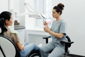 Licensed editorial photograph: provider explains oral care using teeth model